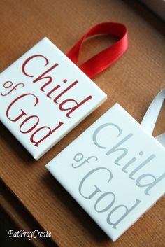 two white signs with red lettering on them sitting on a wooden table next to a ribbon