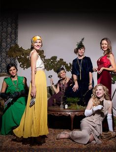 a group of women standing next to each other on a couch in front of a table