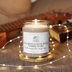 a candle sitting on top of a wooden table next to a string of lights and a guitar