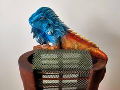 a blue and orange lizard sitting on top of a wooden chair next to a wall