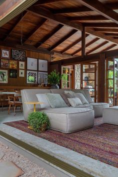 a living room filled with lots of furniture next to a wooden ceiling covered in windows