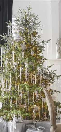 a decorated christmas tree in a living room with silver and white decorations on the top