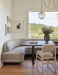 a dining room table with two chairs and a bench in front of a large window