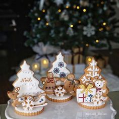 several decorated cookies on a table with a christmas tree in the backgrouf