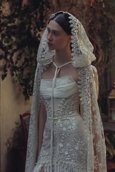 a woman in a white wedding dress with a veil on her head and long sleeves