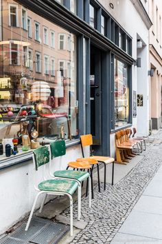 several chairs are lined up in front of a store window on the side of a street