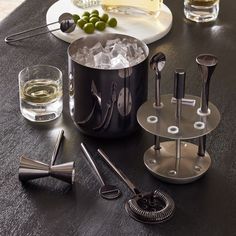 a table topped with ice buckets filled with drinks and utensils next to wine glasses