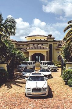 a white car parked in front of a large house with palm trees on the driveway