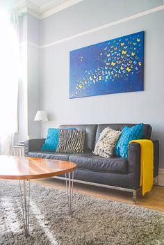 a living room with a couch, coffee table and painting on the wall above it