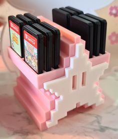 three nintendo gameboy games are sitting on a pink holder with white and black squares