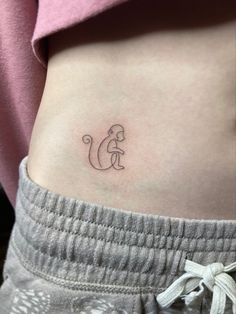 a woman's stomach with a small monkey tattoo on her left side ribcage