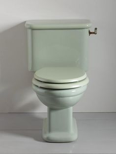 a white toilet sitting on top of a floor next to a bathroom wall with the lid up