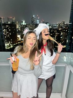 two women dressed up as cats and mouse holding utensils in front of cityscape