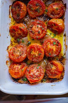 tomatoes in a white casserole dish with parsley on top and melted cheese