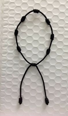 a string bracelet with black beads on a white background