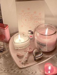 a candle and some other items are on a heart shaped tray next to a card