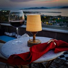 a glass of wine sitting on top of a table next to a lamp