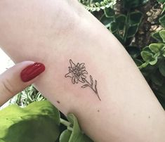 a woman's arm with a small flower tattoo on the back of her left arm