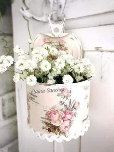 white flowers are in a bucket hanging from a hook on a doorknobl