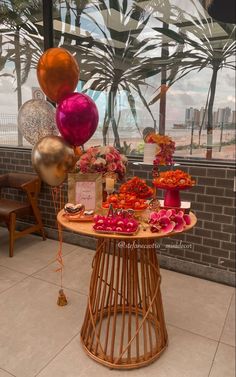 a table topped with lots of different types of flowers and balloons in front of a window