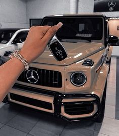 a hand holding a cell phone in front of a mercedes benz suv at a dealership