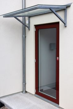 an open red door on the side of a white building