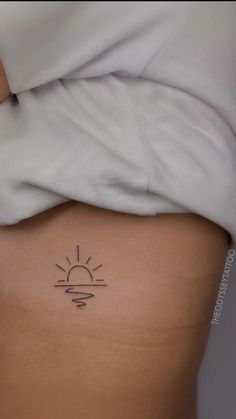 the back of a woman's stomach with a small sun tattoo on her left side