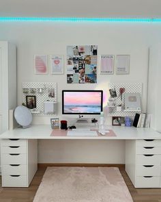 a white desk topped with a computer monitor next to a wall covered in pictures and photos