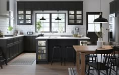 a large kitchen with black cabinets and white counter tops is pictured in this image, there are stools at the end of the table