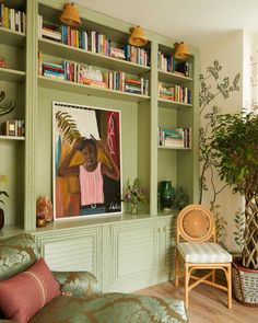 a living room filled with lots of green furniture and bookshelves next to a potted plant