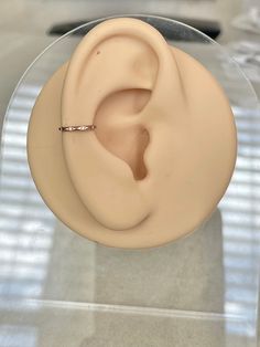 a fake ear sitting on top of a glass display case with a ring in it