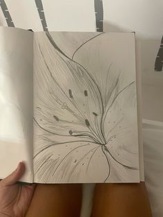 a drawing of a flower is being held up by someone's hand in front of them