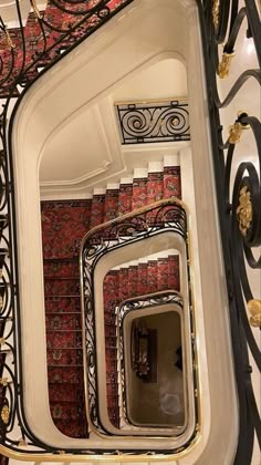 an ornate staircase with red carpet and black iron railings