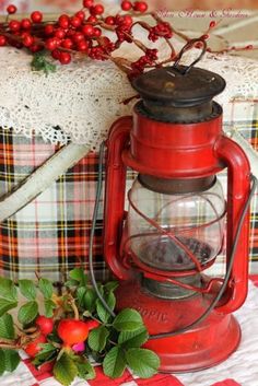 a red lantern sitting on top of a table next to some berries and holly branches