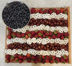 an american flag made out of strawberries and other fruit on a table with a bowl of berries