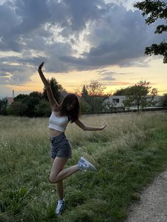 a woman is running through the grass with her arms in the air as she stretches