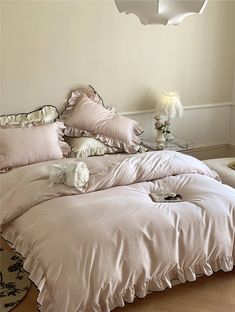 a bed with pink sheets and pillows in a room