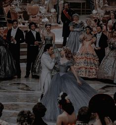 a group of people standing around each other in formal dress and tiaras, all dressed up