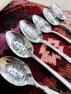 five spoons with different designs on them are sitting on a colorful rug and one is empty