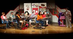 a group of people sitting on top of a stage next to each other in chairs