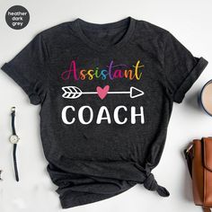 "Assistant Coach Shirt, Coach T-shirt, Sports Coach Apparel, Baseball Coach Gift, Cute Coach T-shirt, Instructional Coach Shirt * Unisex T Shirt: \"Bella Canvas\" - Retail fit, Runs true to size. - Solid colors: 100% Ring-Spun soft cotton. Heather colors: 52% Ring-Spun cotton 48% polyester. * V-Neck T Shirt: \"Bella Canvas\" - Retail fit, Runs true to size. - Solid colors: 100% Ring-Spun soft cotton. * Women's T Shirt: \"Anvil\"  Feminine cut, Runs smaller than usual (Please use the size chart). - 100% Ring-Spun soft cotton. - Color \"Dark Grey\" is: \"Heavy Metal\". And color \"Athletic Heather\" is: \"Grey Heather\" in Women's shirts.                                                                                                   * Unisex T Shirt: \"Gildan Softstyle\" - Runs true to siz Casual Multicolor T-shirt With Team Name, Sporty Multicolor Short Sleeve T-shirt, Multicolor Cotton Tops With Team Name, Multicolor Team Name Short Sleeve Top, Multicolor Short Sleeve Top With Team Name, Multicolor Short Sleeve Sports Tops, Multicolor Crew Neck T-shirt With Name Print, Multicolor Crew Neck T-shirt For Sports, Multicolor Crew Neck Sports T-shirt