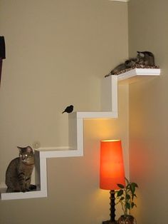 a cat sitting on top of a set of stairs next to a lamp and potted plant