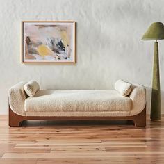 a white couch sitting next to a lamp on top of a hard wood floor in front of a wall