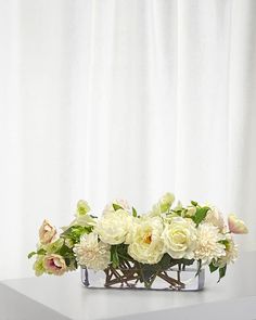 a vase filled with white and pink flowers on top of a table next to a curtain