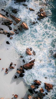 an aerial view of the ocean with rocks and water