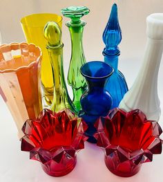 several different colored vases sitting next to each other on a white table top,