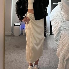 a woman standing in front of a mirror wearing a white skirt and black blazer