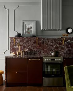 a kitchen with marble counter tops and wooden cabinets in the corner, along with a green chair