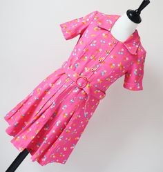 SUPER CUTE! Perfectly formed 1970's summer mini-dress in bright bubblegum pink cotton patterned with daisies and blue cherries. The cotton is a dense high quality and the colours are crisp. Details include the semi-pleated skirt, decorative button trim and matching buckle belt. The old vintage size label says '38' but in my opinion the fit is much smaller and like an XXS / XS or a UK 6 / 8 We advise that you check all the measurements below. The garment is mid-weight and is lined. Excellent Cond Pink Casual Dress With Retro Print, Fitted Pink Cotton Dress, Casual Pink Dress With Retro Print, Spring Retro Print Short Sleeve Dresses, Spring Retro Print Dresses With Short Sleeves, Retro Print Short Sleeve Dresses For Spring, Pink Retro Print Summer Dress, Retro Pink A-line Dress, Vintage Pink Mini Length Dress