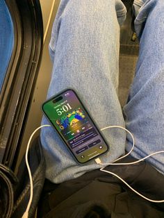 a cell phone is hooked up to a charger in someone's lap on the train